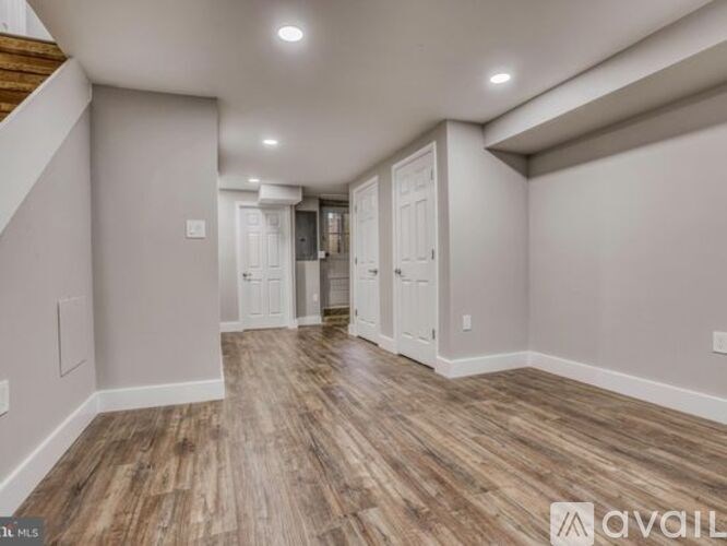 A spacious room with wooden flooring and white walls.