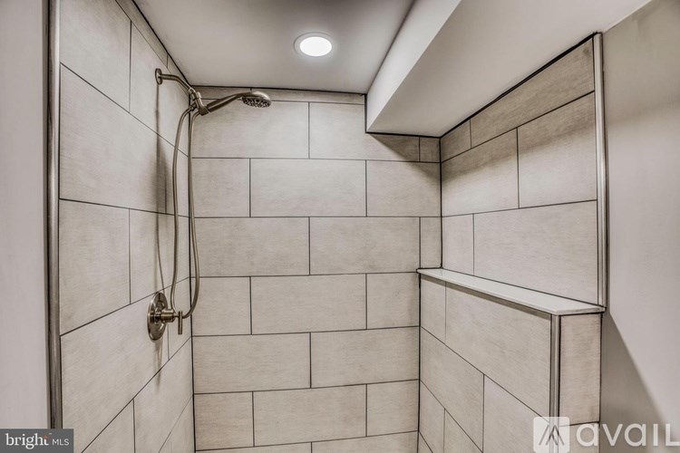A shower area with a wall of tiles and a shower head.