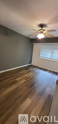 A room with a ceiling fan and wooden flooring.