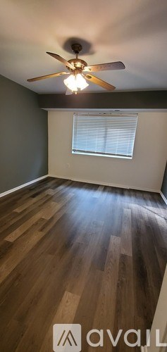 A room with a ceiling fan and wooden flooring.