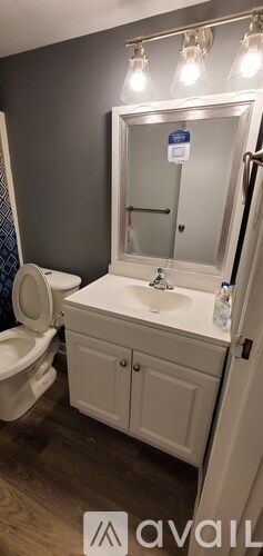 A bathroom with a toilet, sink, and mirror.