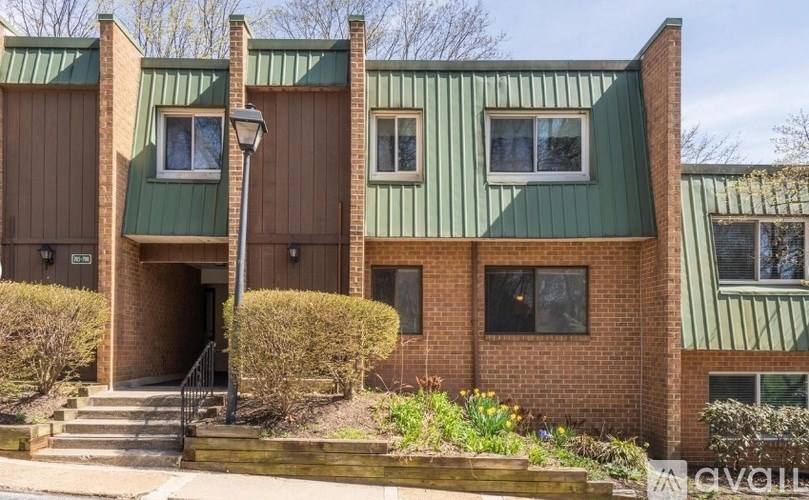 A building with a green roof and brick walls has a sign that says "AVAILABLE".