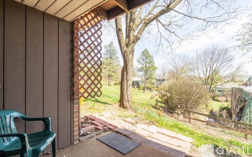 A patio with a green chair and a lattice screen door.