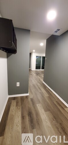 A room with wooden flooring and a flat screen TV mounted on the wall.