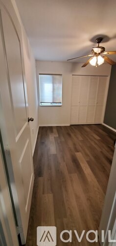 A hallway with wood flooring and a ceiling fan.