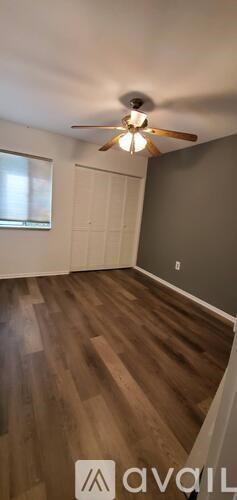 A room with a ceiling fan and wooden flooring.