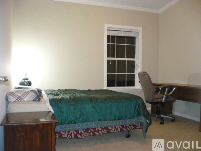 A bedroom with a bed, desk, and chair.