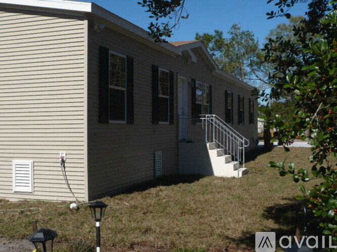 A beige house with black shutters and a white door.