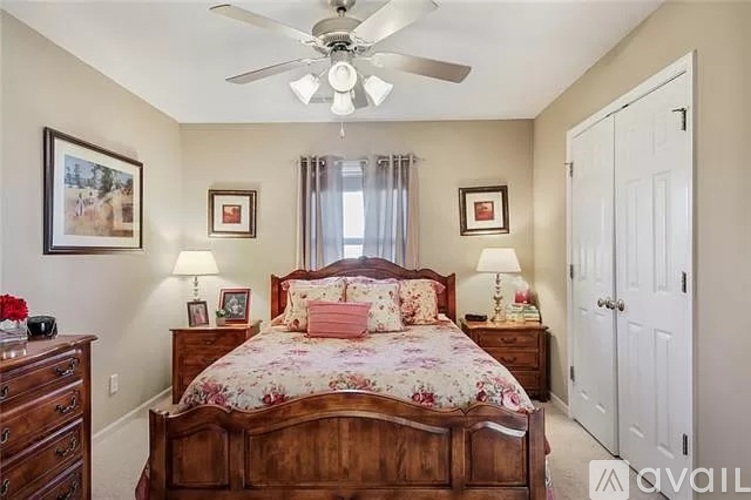 A bedroom with a large bed, a dresser, and a ceiling fan.