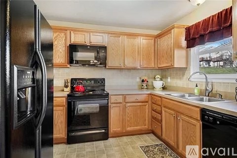 A kitchen with wooden cabinets and black appliances.