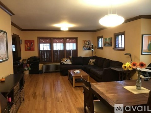 A living room with a black couch and wooden floors.