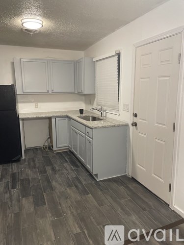 A kitchen with white cabinets and a black refrigerator.