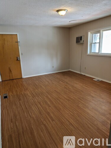 A room with wooden flooring and a door on the left.
