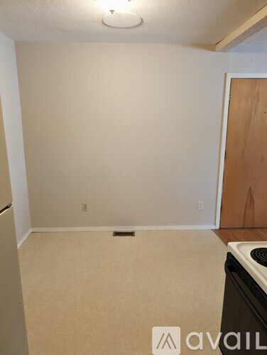 A room with a beige carpet and a wooden door.