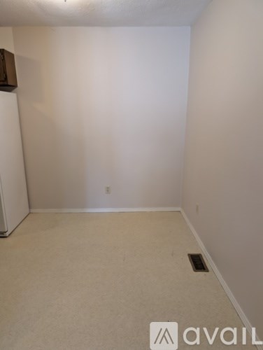 A room with a white wall and a brown object on the left.