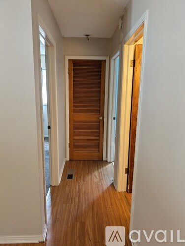 A hallway with a wooden floor and a door on the right.