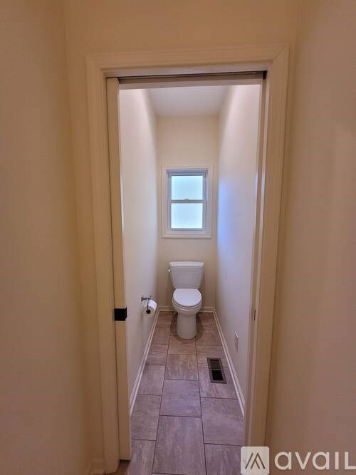A bathroom with a toilet and a window.