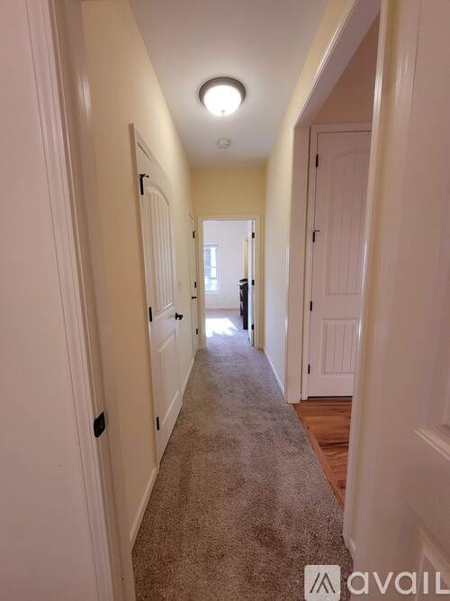 A long hallway with white walls and a carpeted floor.