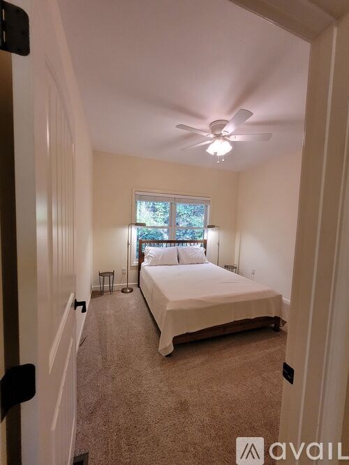A bedroom with a bed, a ceiling fan, and a window.