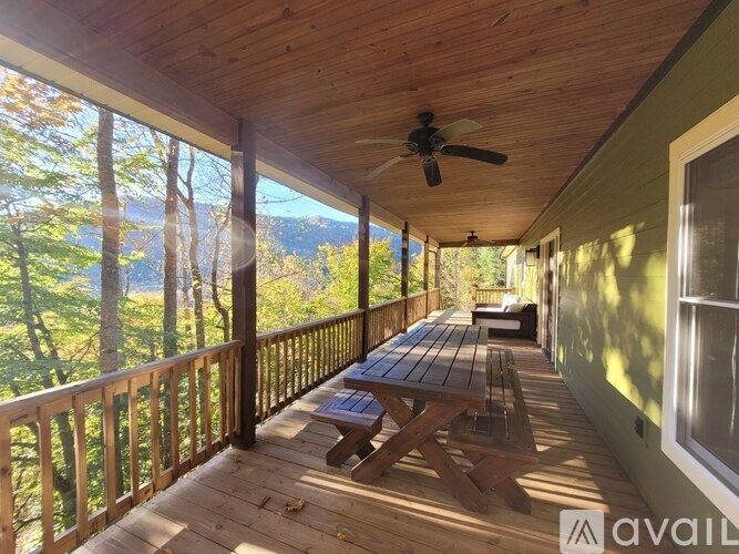 A wooden deck with a table and chairs overlooking a forest.