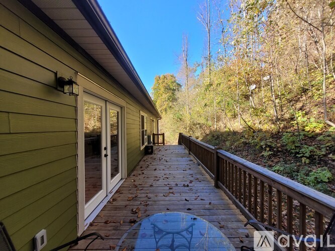 A deck with a table and chairs overlooking a wooded area.