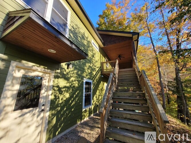 A house with a green exterior and a wooden staircase leading to the second floor.