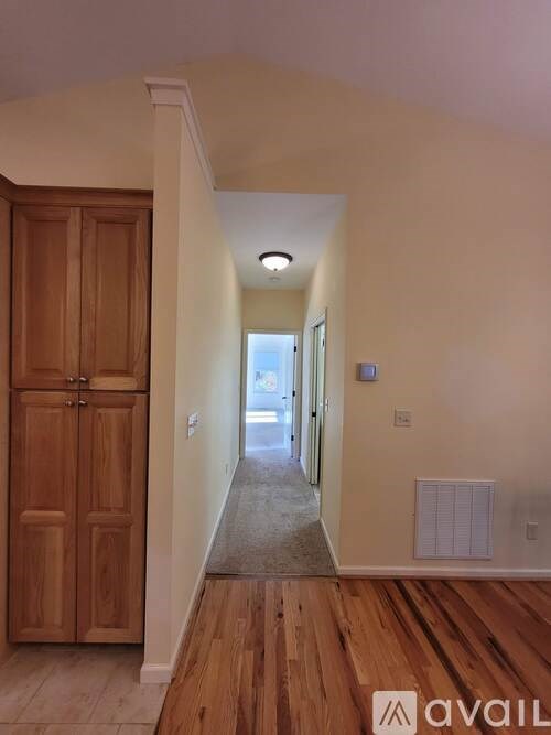 A hallway with a wooden floor and a door on the left.