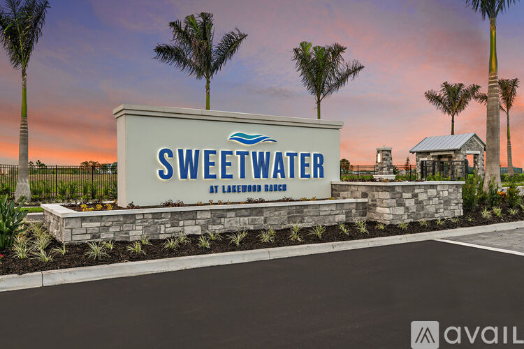 A sign that says Sweetwater in front of some palm trees.