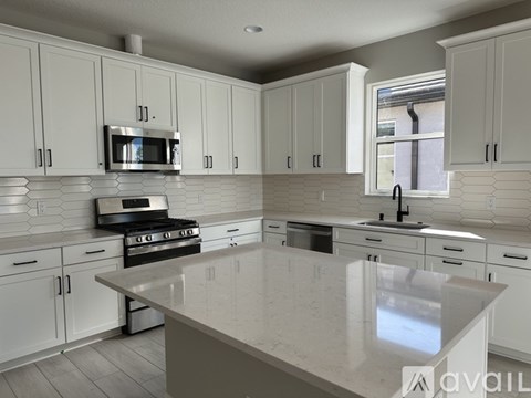 A kitchen with white cabinets and a large island.