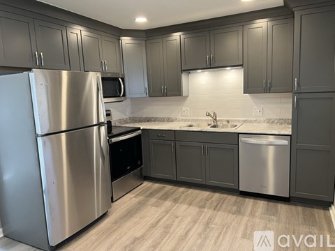 A kitchen with a stainless steel refrigerator and cabinets.