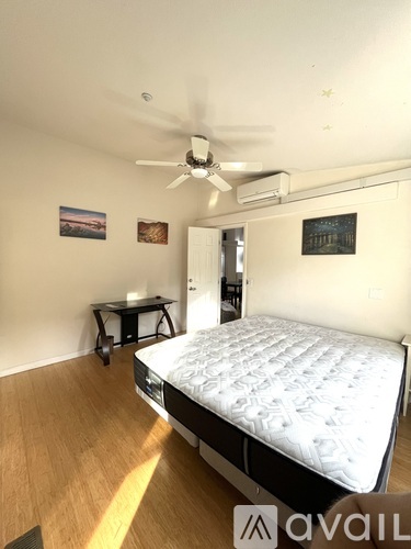 A bedroom with a bed, a table, and a ceiling fan.