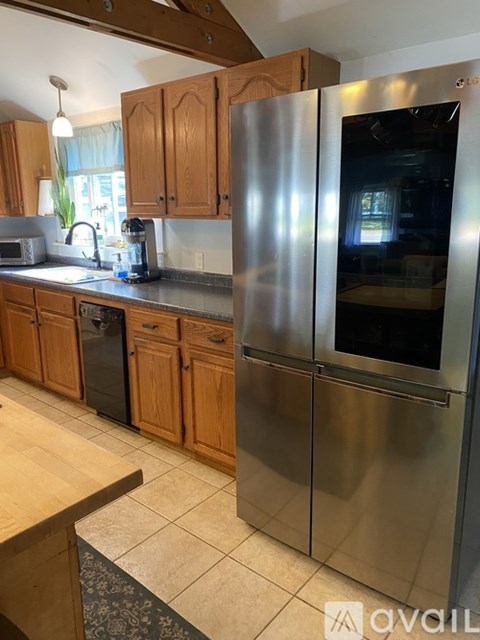 A kitchen with a stainless steel refrigerator and wooden cabinets.