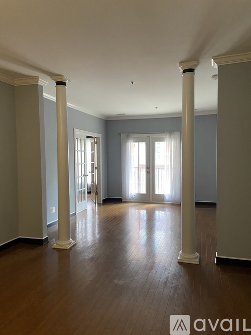 A spacious room with wooden floors and white columns.