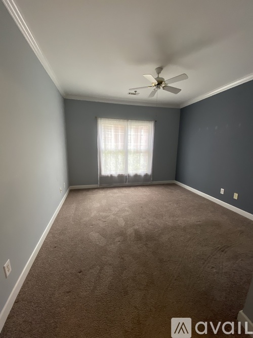 A room with a ceiling fan and carpeted floor.