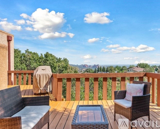 A balcony with a table and chairs overlooking a mountainous landscape.