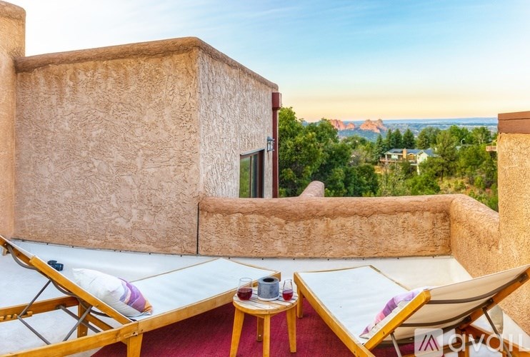A tan adobe building with a balcony overlooking a mountainous landscape.