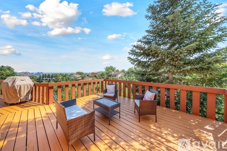 A wooden deck with a table and chairs overlooking a mountainous landscape.