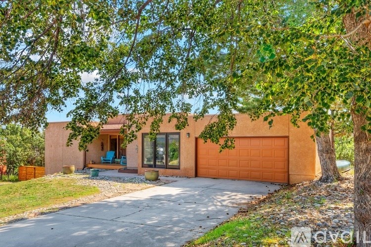 A house with a brown garage door is surrounded by greenery.
