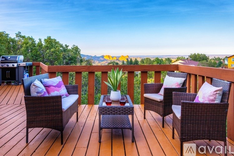 A wooden deck with wicker furniture and a view of the mountains.