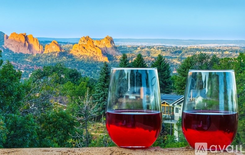 Two glasses of red wine are in the foreground with a scenic view of a mountain range in the background.
