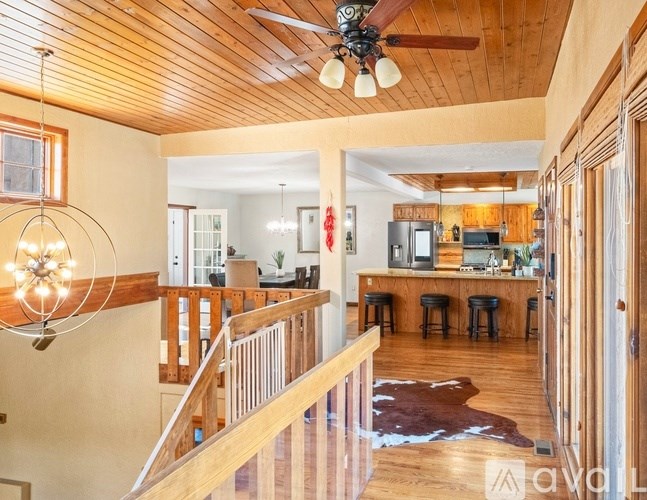A wooden ceiling fan hangs over a living room with a bar area.