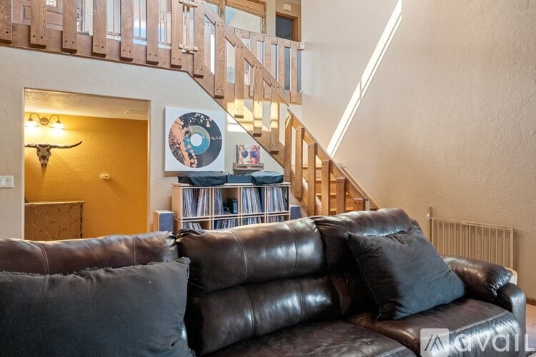 A brown leather couch with two grey pillows sits in a living room.
