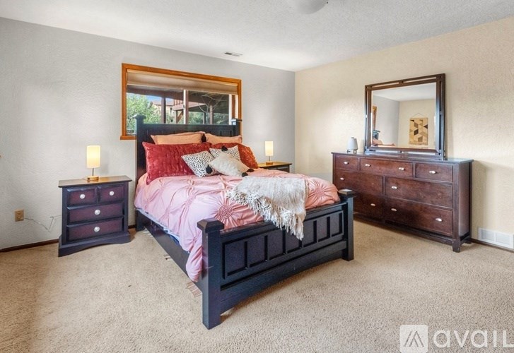 A bedroom with a bed, dresser, and mirror.