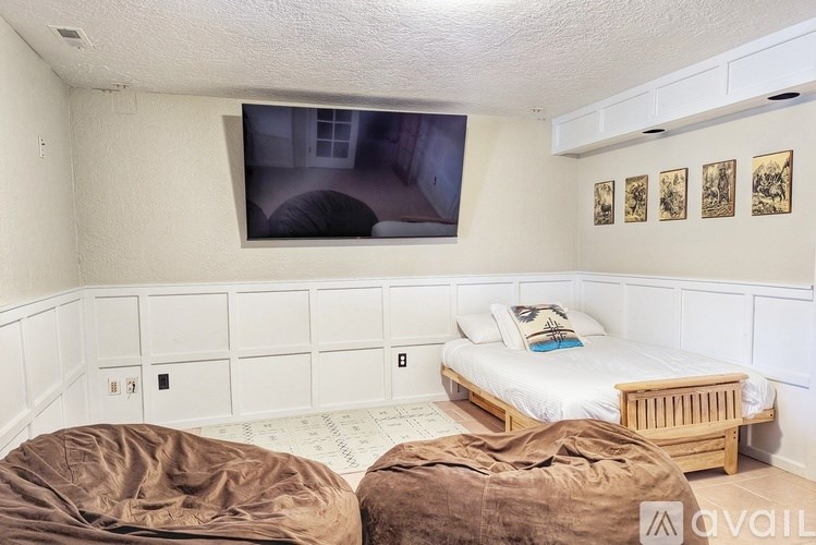 A bedroom with a bed, a couch, and a wall-mounted television.