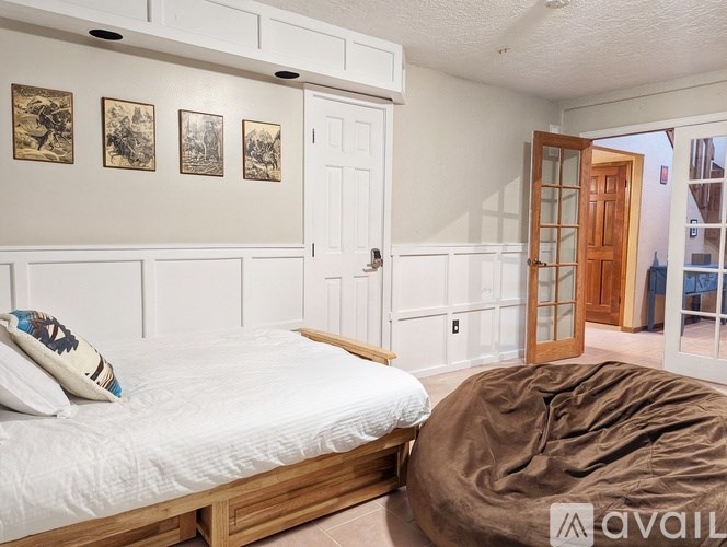 A bedroom with a bed, a chair, and pictures on the wall.