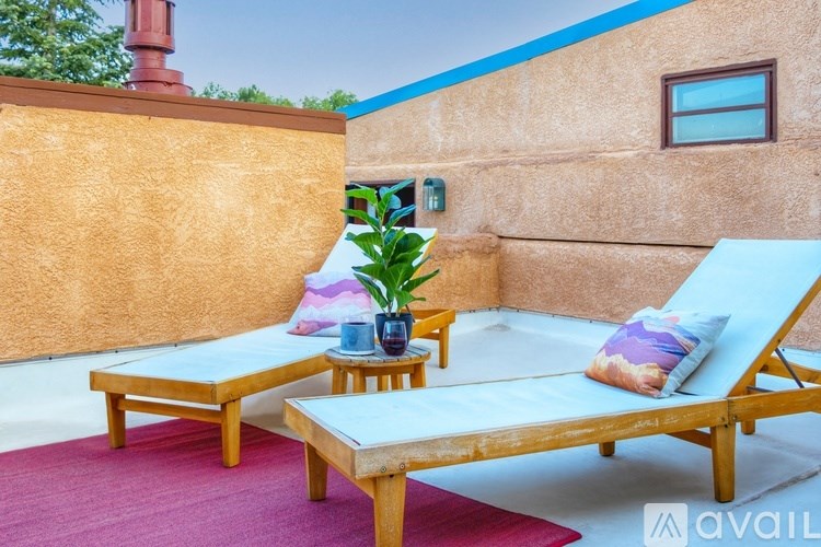 A wooden lounge chair with a blue cushion is on a patio.