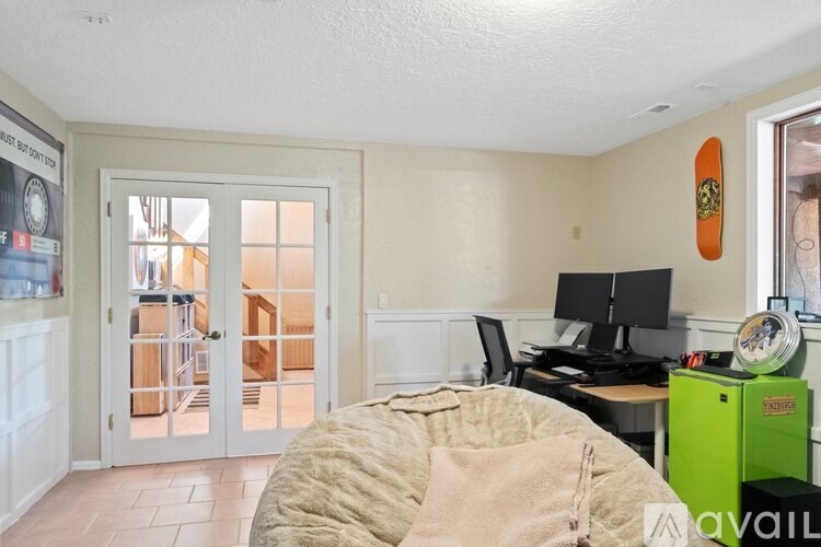 A room with a bed, desk, and a window with a view of a deck.