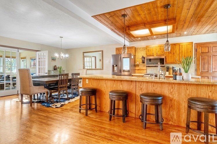 A kitchen with wooden cabinets and a bar area with stools.