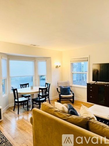 A living room with a yellow couch and a dining table with chairs.