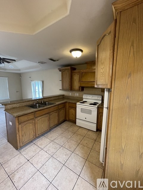 A kitchen with wooden cabinets and a tiled floor.